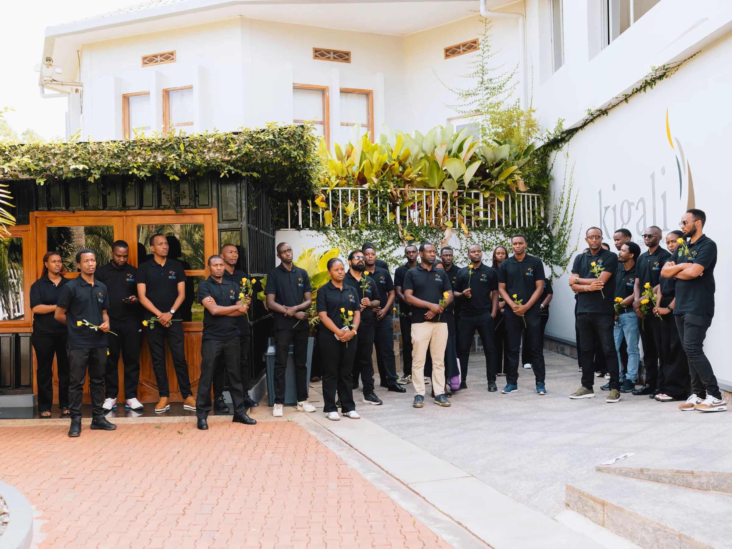 The team standing outside the memorial, holding flowers