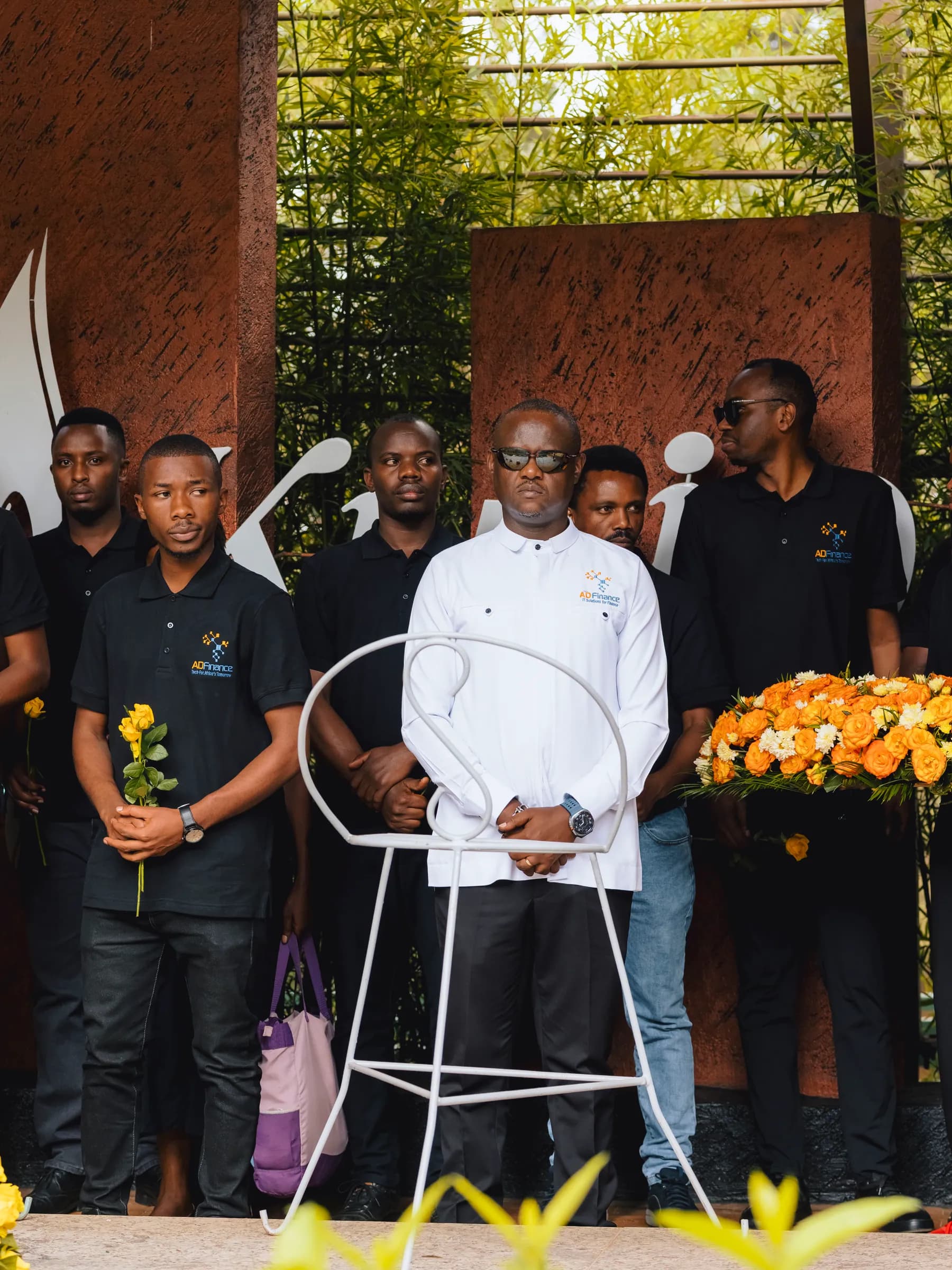 Team members standing beside a wreath of orange flowers