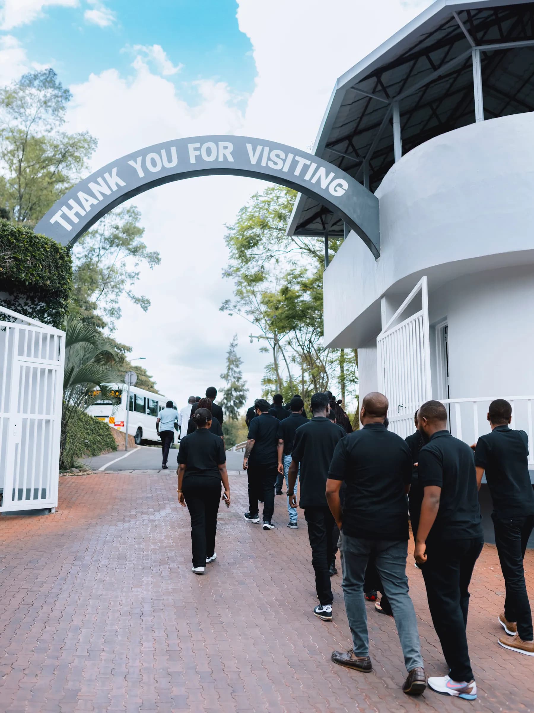 Team members walking out under the memorial's “Thank you for visiting” arch