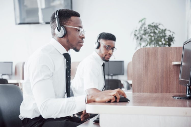 African american customer support operator with hands-free headset working in the office